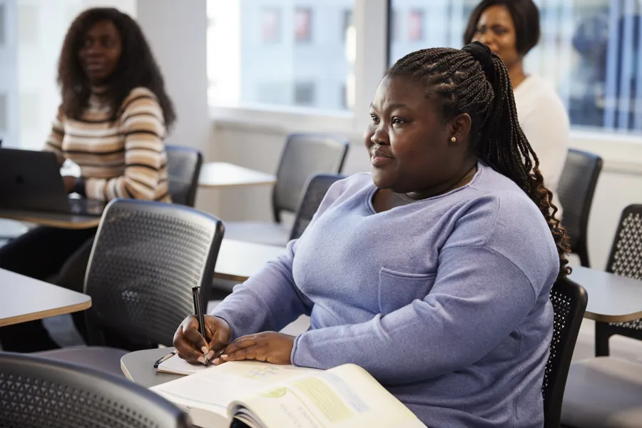 A student taking notes and listening during a lecture in a classroom